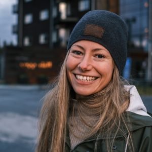 A portrait of a smiling blonde caucasian female in a coat and hat in winter